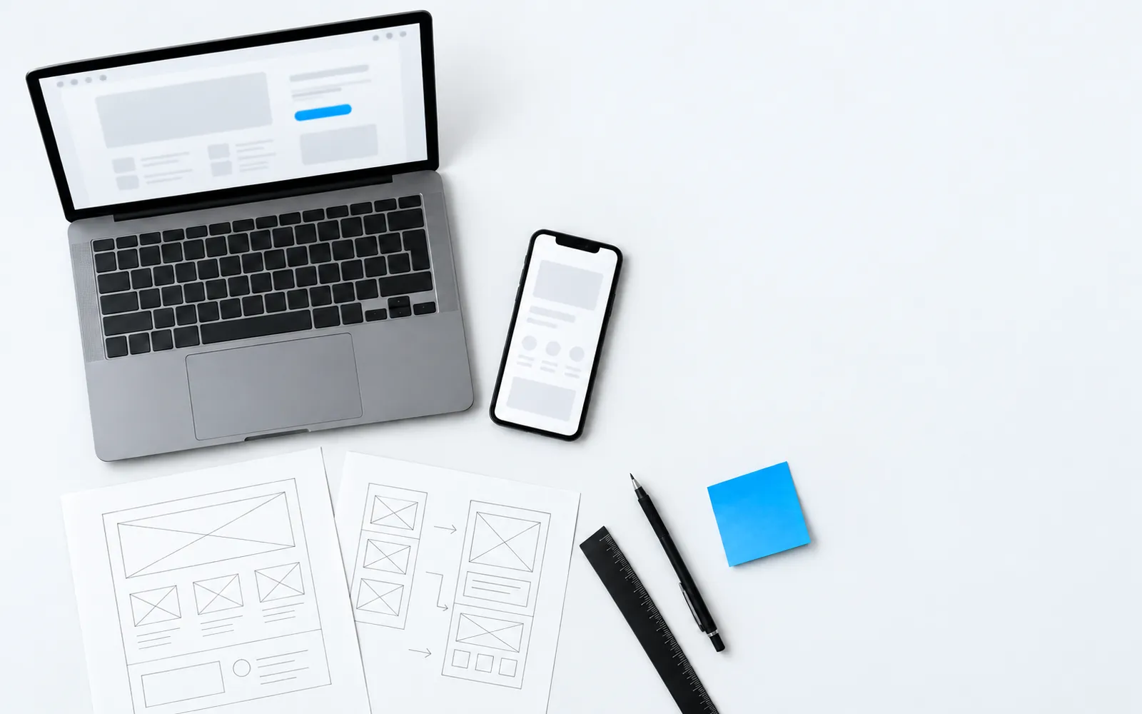 Workbench with a laptop, a phone and interface sketches